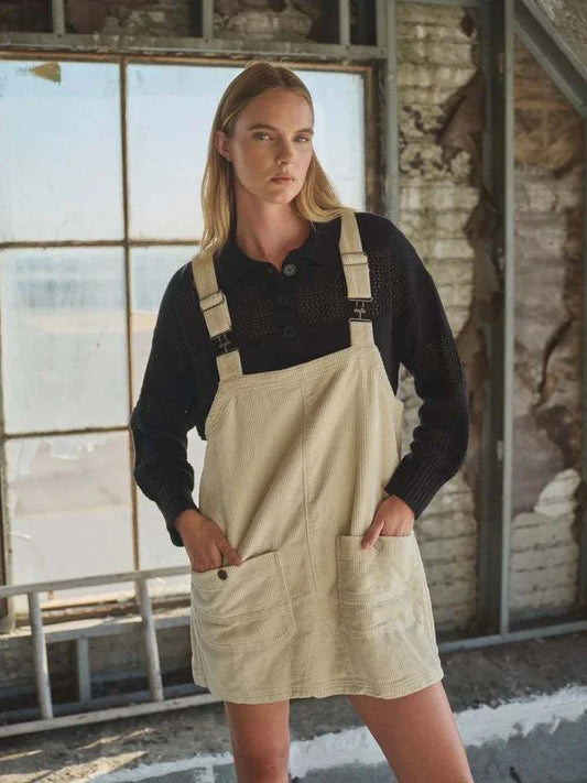 Corduroy Overall Mini Dress with adjustable straps and button-down front, styled with a black top.