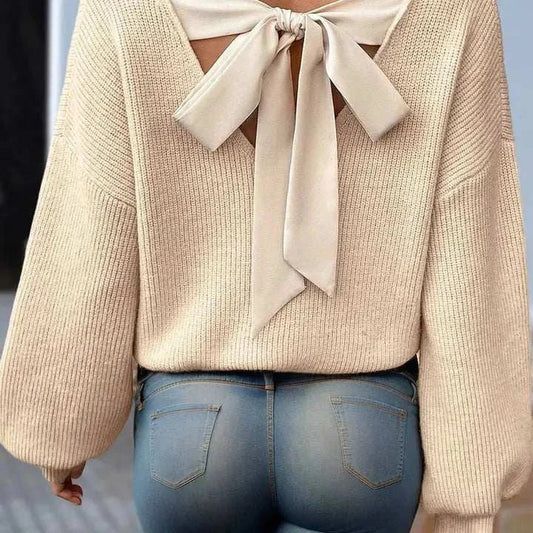 Beige puff sleeve sweater with bow knot detail on the back, worn with jeans.