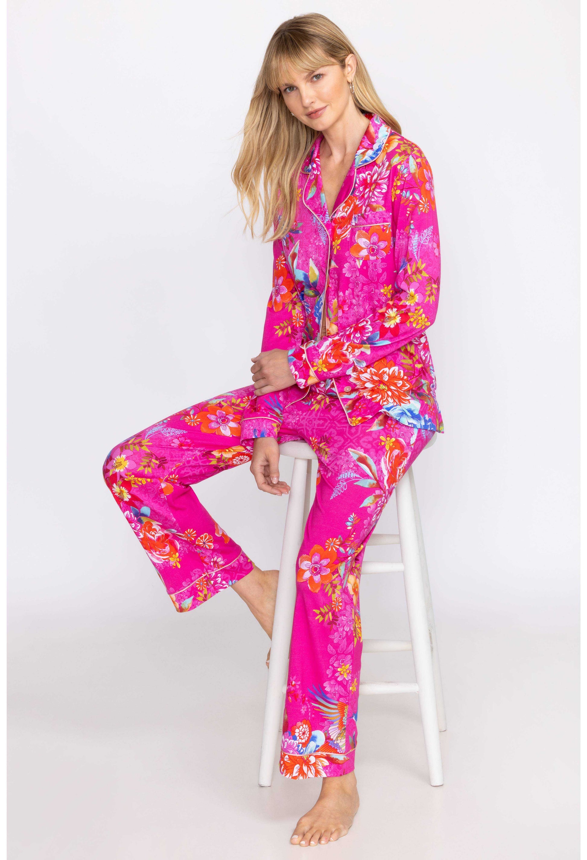 Carly Pj Set in vibrant pink floral print on model sitting on stool.